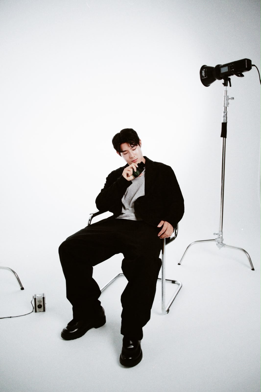 Older man wearing dark sunglasses and a navy sweater sitting at a table, holding a white gift box with a red ribbon, with text saying 'Sunnies that say "I know what I like"'.