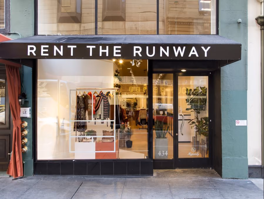 Storefront of Rent the Runway boutique with black awning and visible clothing inside.