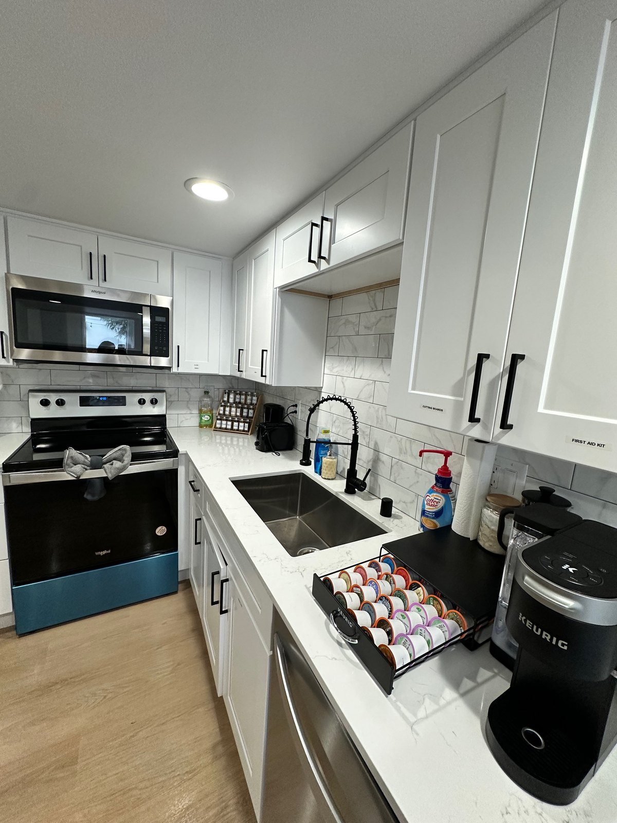 Newly installed white shaker kitchen cabinets with black hardware and stainless appliances in a Seattle home.