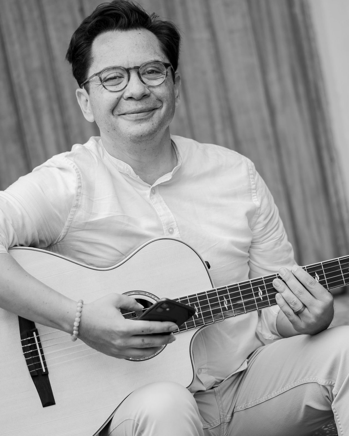 David Lindes smiling, seated with his guitar