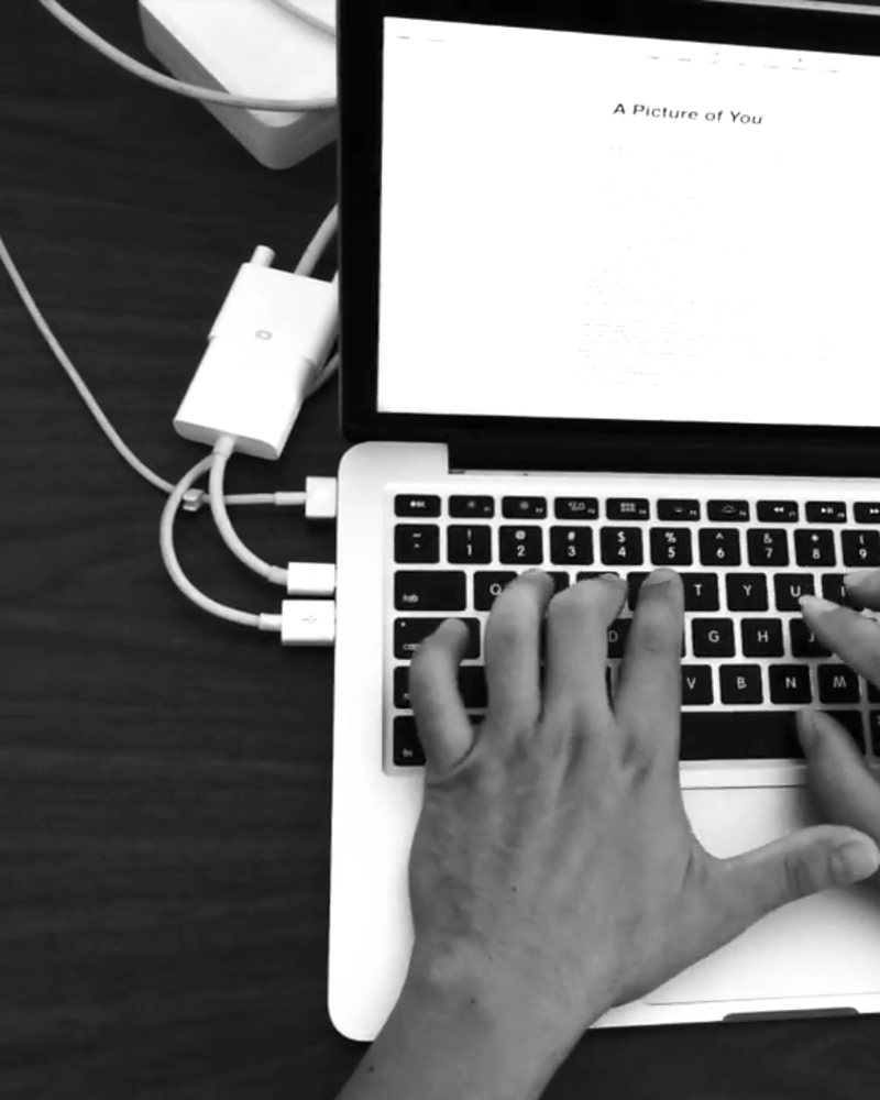 David's hands typing the lyrics of A Picture of You on a laptop