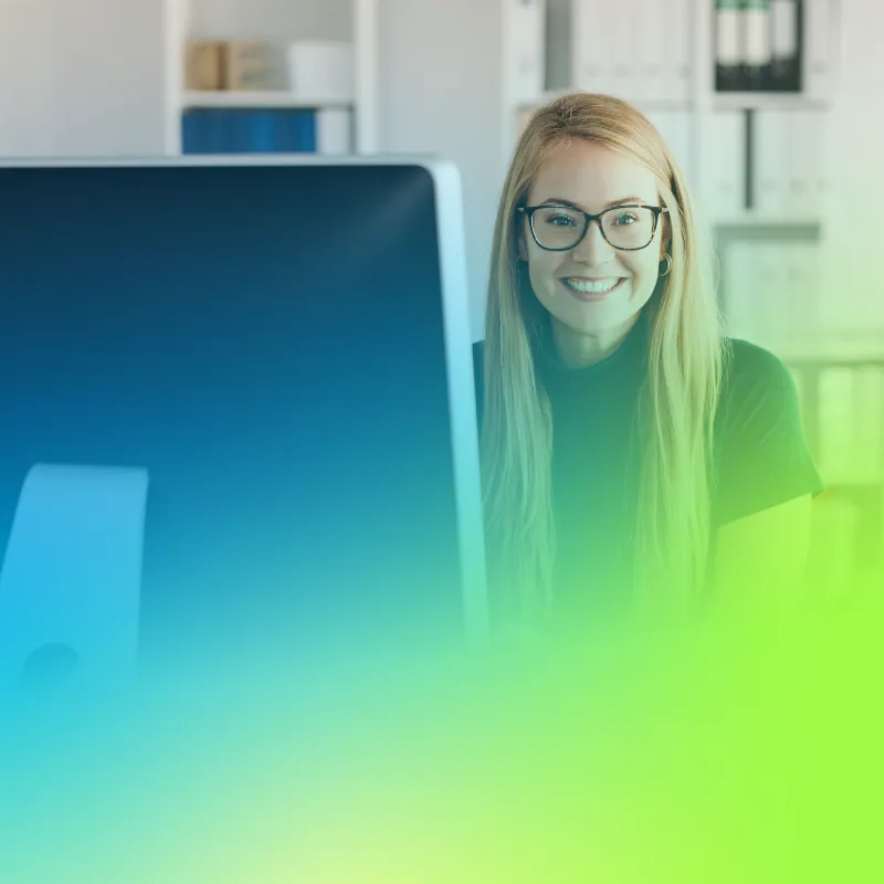 A young woman account executive looking past her computer screen at the camera smiling