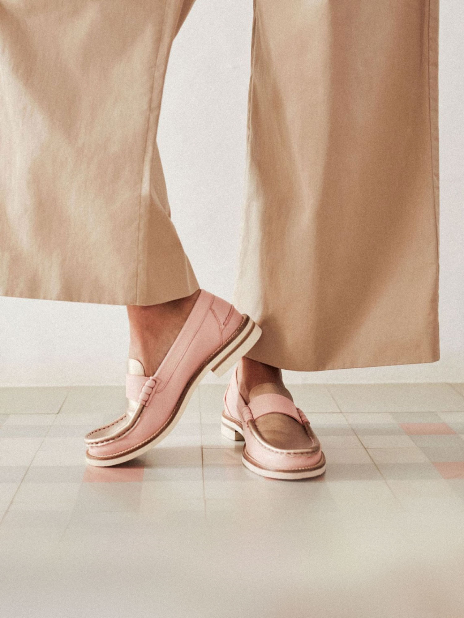Bottom of a woman's legs with beige tousers and pink shoes.
