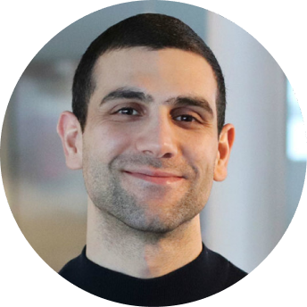 Portrait of a young man with short dark hair and a slight smile wearing a black shirt.