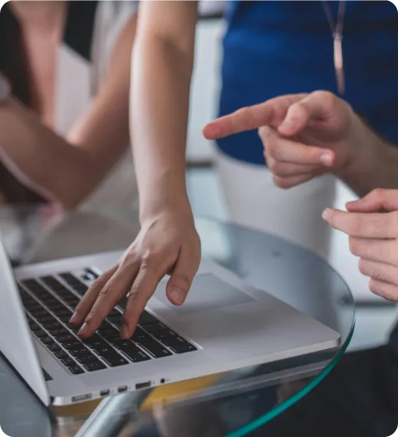 A close up image of two people collaborating over a laptop.