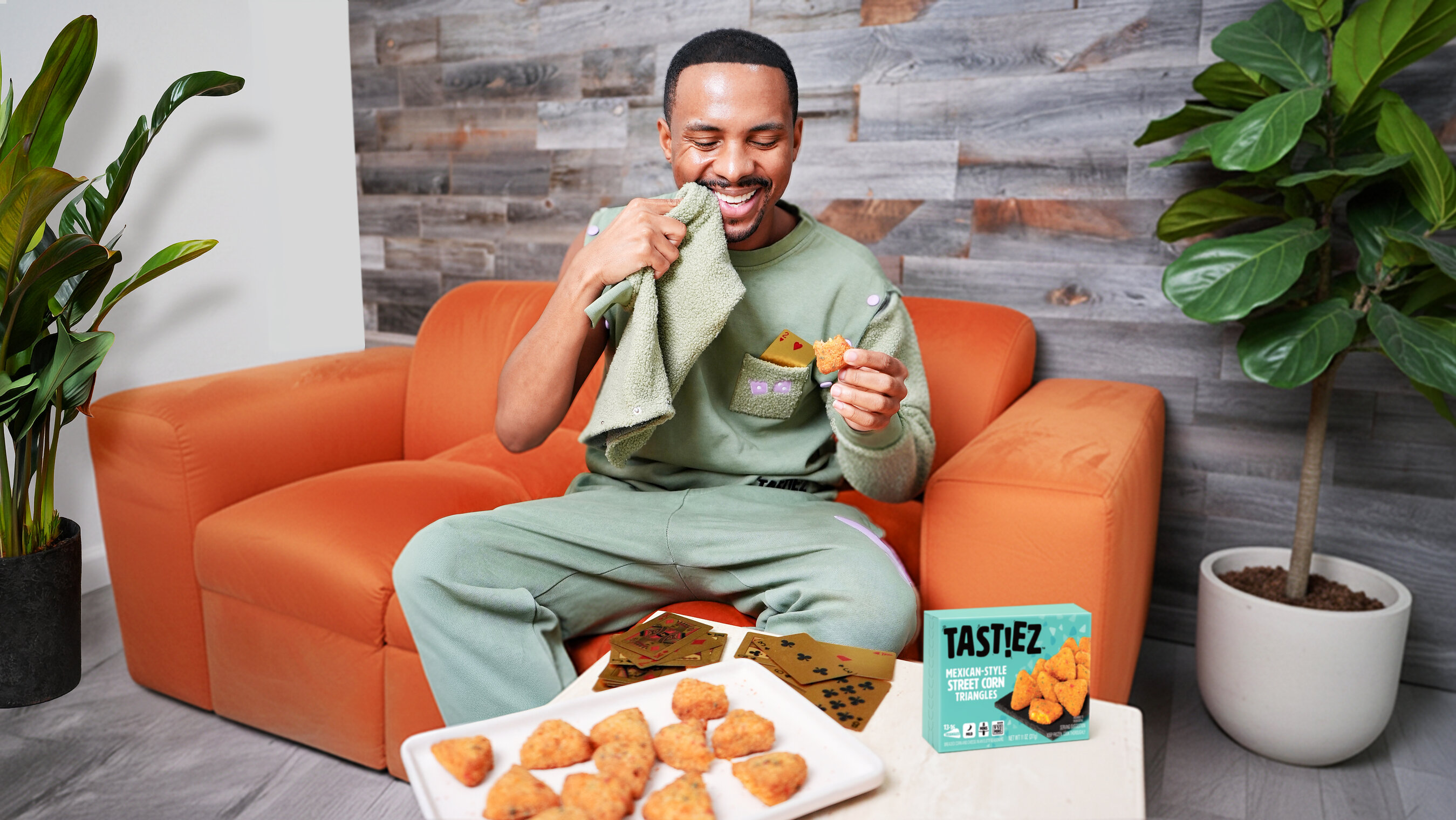 A person wearing the TAST!EZ sweatsuit uses its detachable sleeve as a napkin while seated at a game-night table
