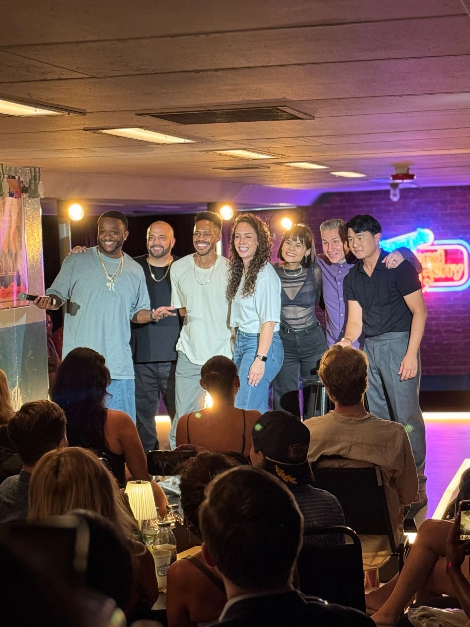 The comedy lineup on stage with guests in the audience