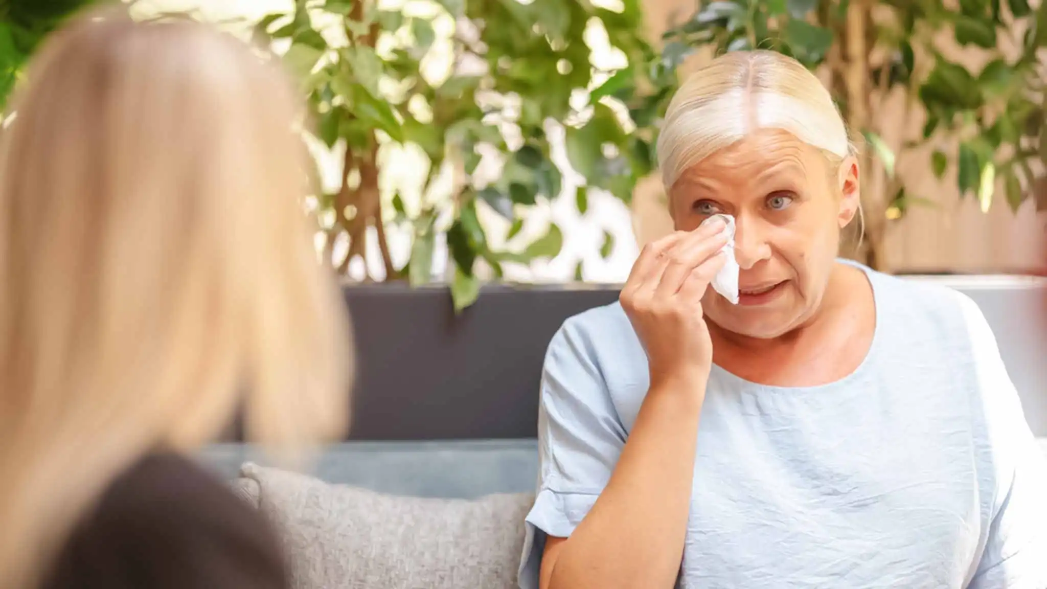 Eine Patientin tupft sich mit einem Taschentuch die Tränen aus dem Gesicht. Sie spricht mit einer Therapeutin.