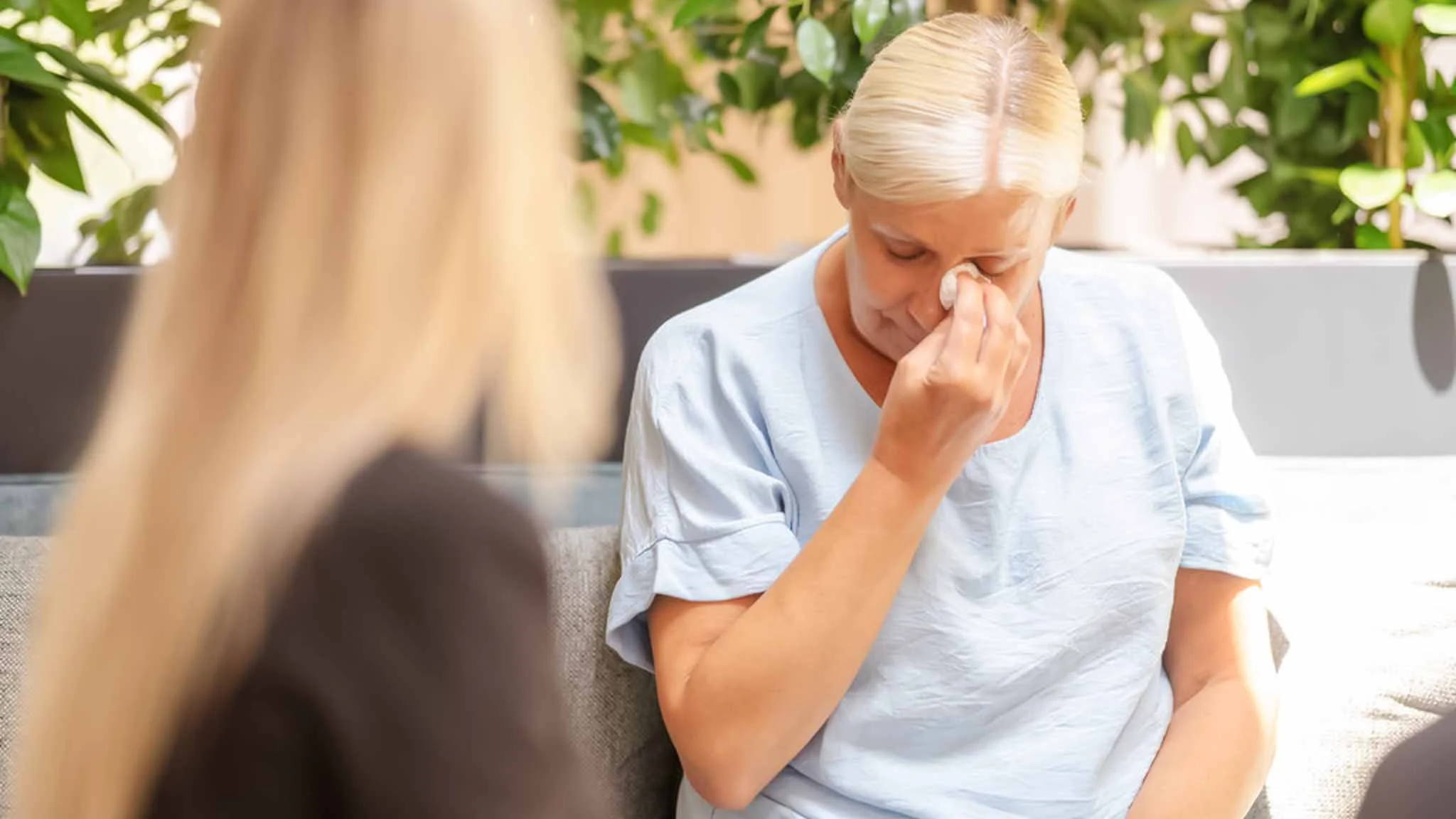 Eine Patientin tupft sich mit einem Taschentuch die Tränen aus dem Gesicht. Sie spricht mit einer Therapeutin.