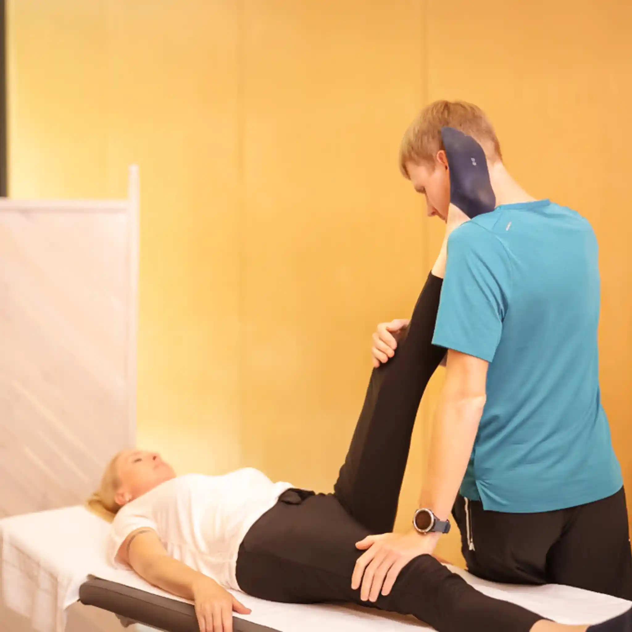 Eine Patientin liegt bei der Physiotherapie mit einem Therapeuten auf einer Liege. 