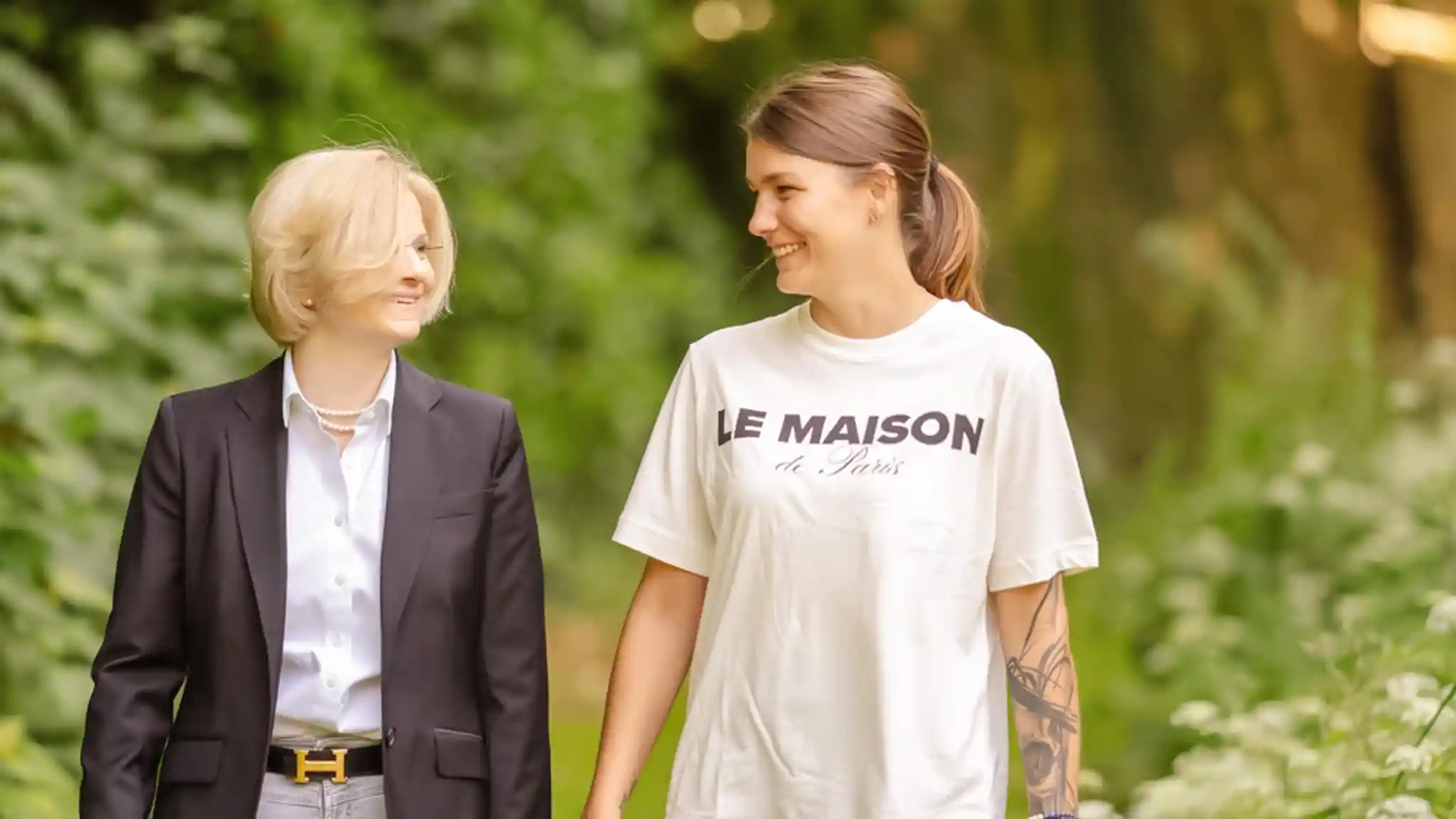 Eine Ärztin spaziert neben einer Patientin und sie blicke einander lachend an.