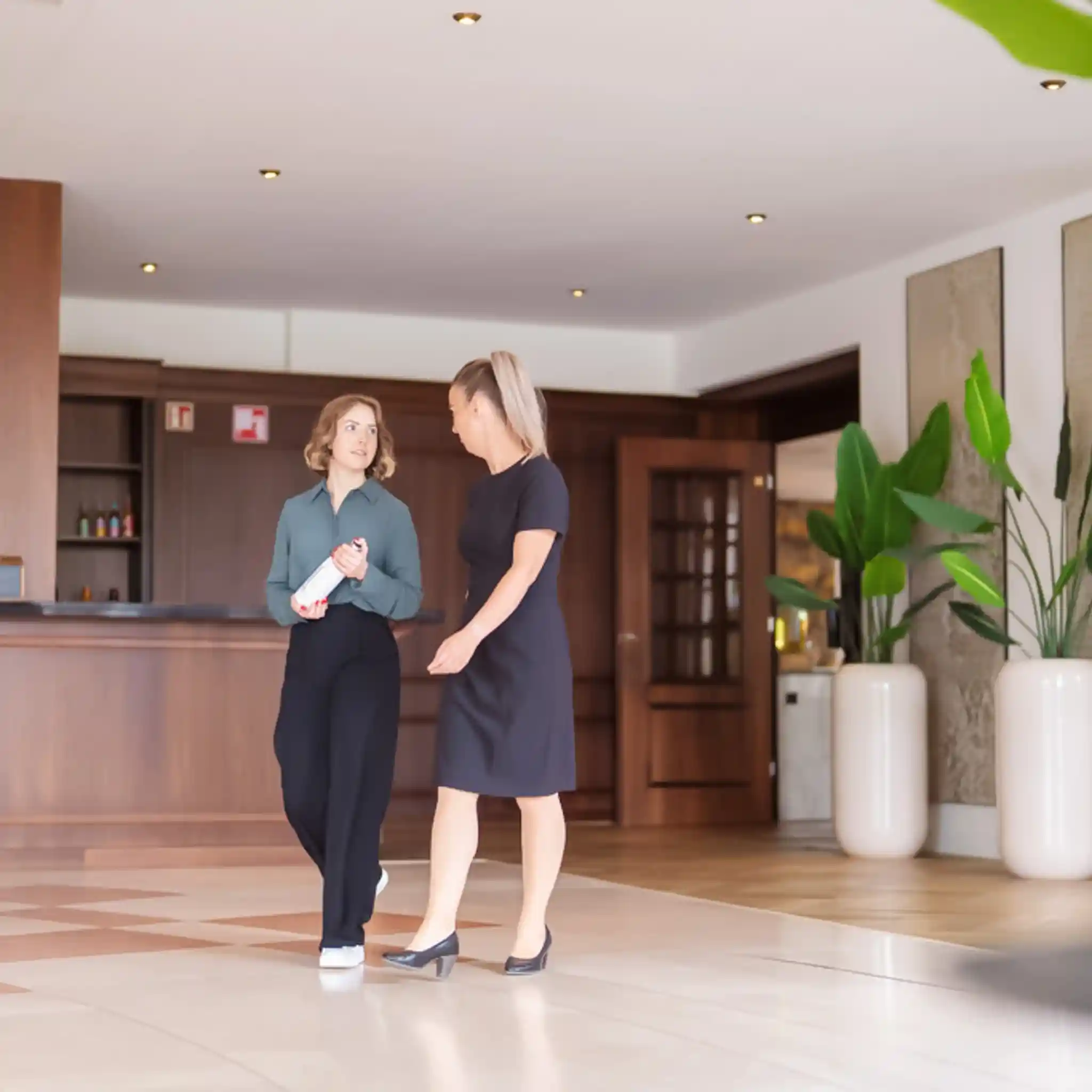 Eine Patientenmanagerin und eine Patientin laufen gemeinsam durch den Eingangsbereich und unterhalten sich.