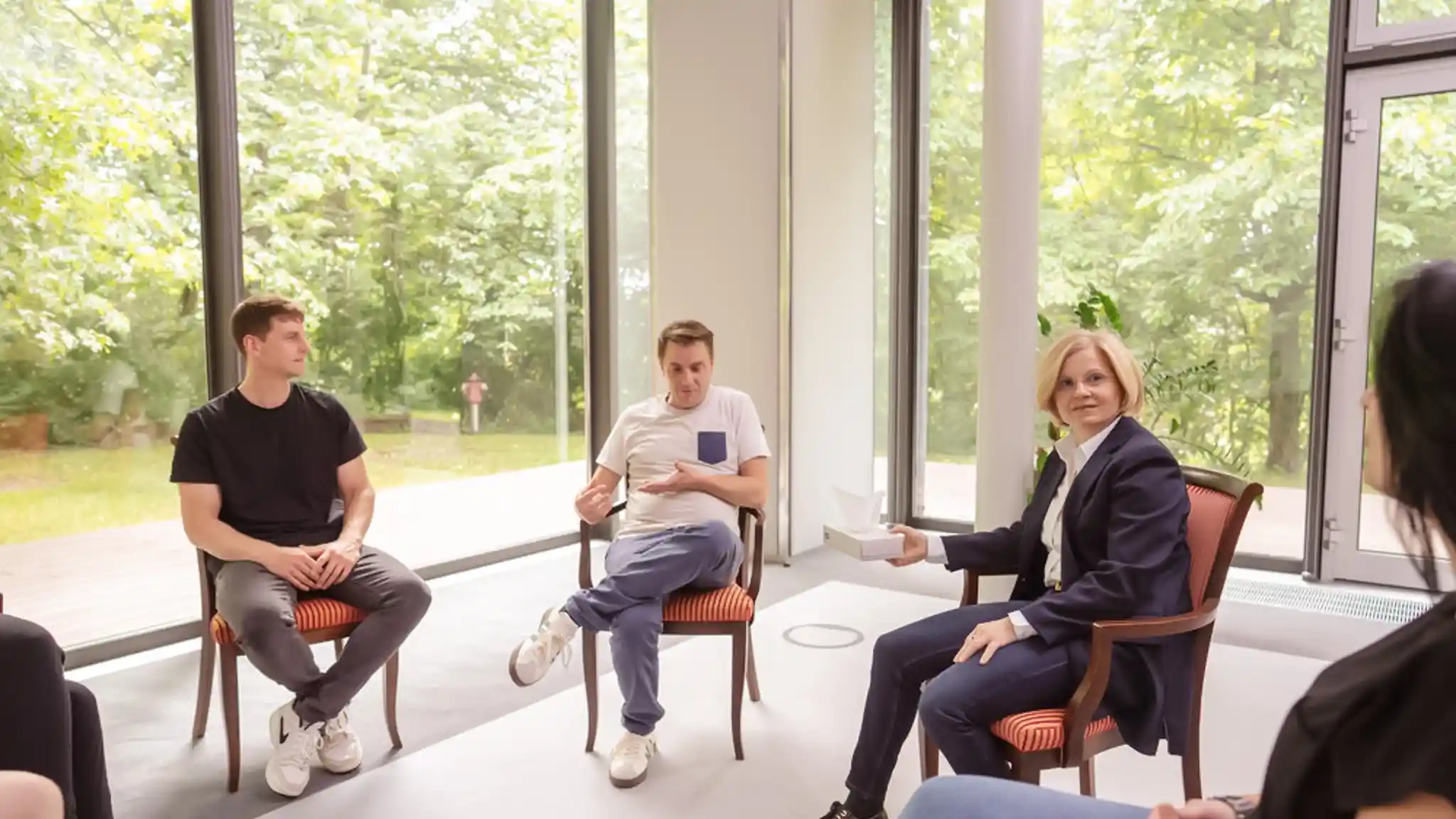 Gruppentherapiesitzung mit mehreren Patienten und einer Ärztin