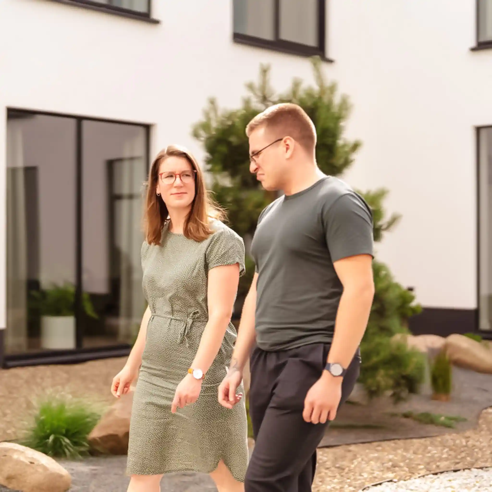 Ein Mann und eine Frau laufen gemeinsam durch den Innenhof und unterhalten sich.
