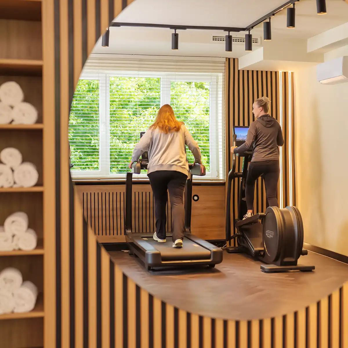 Zwei Patienten trainieren nebeneinander an Geräten im Fitnessraum.