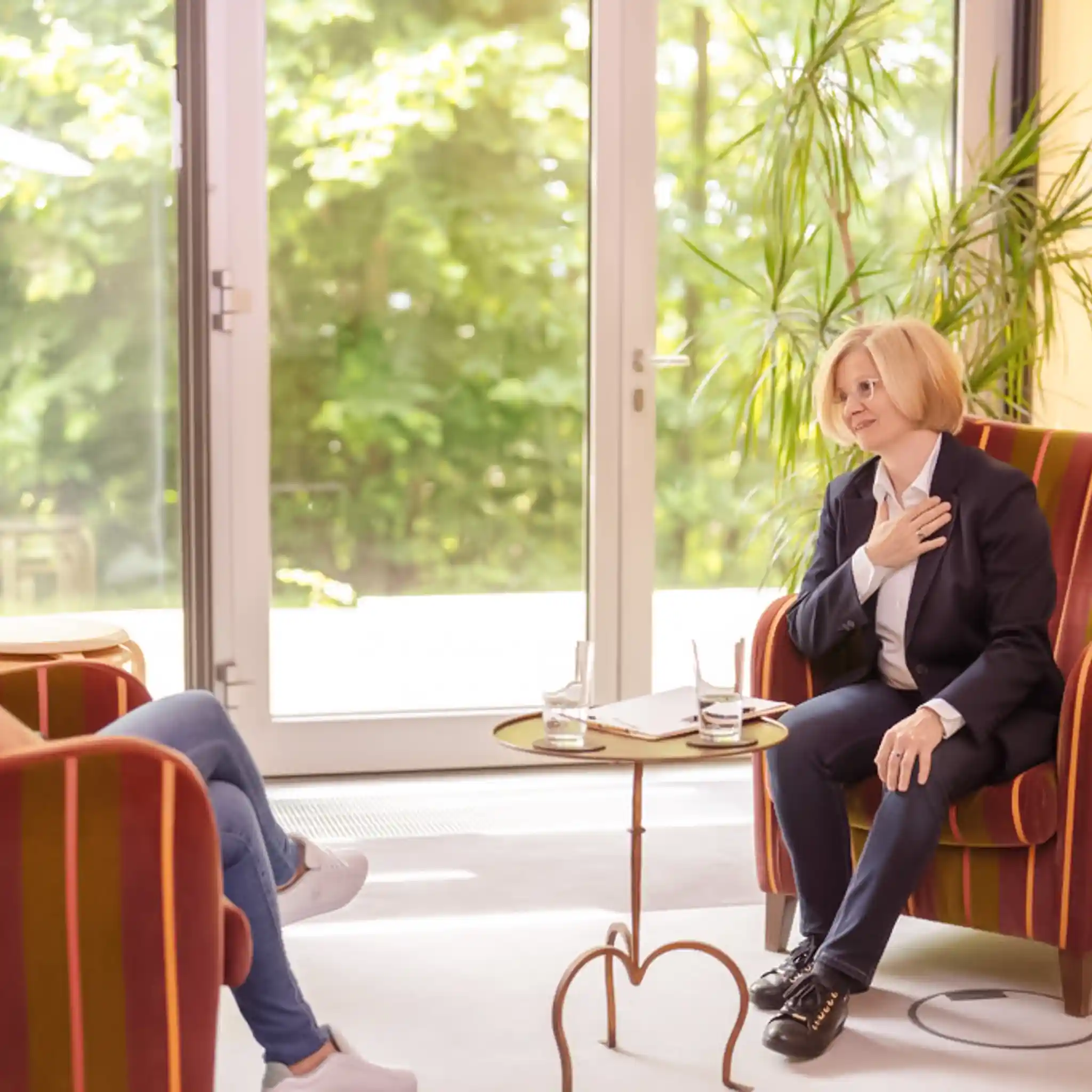 Eine Ärztin im Therapiegespräch mit einer Patientin. Sie fasst sich mit der Hand ans Herz.