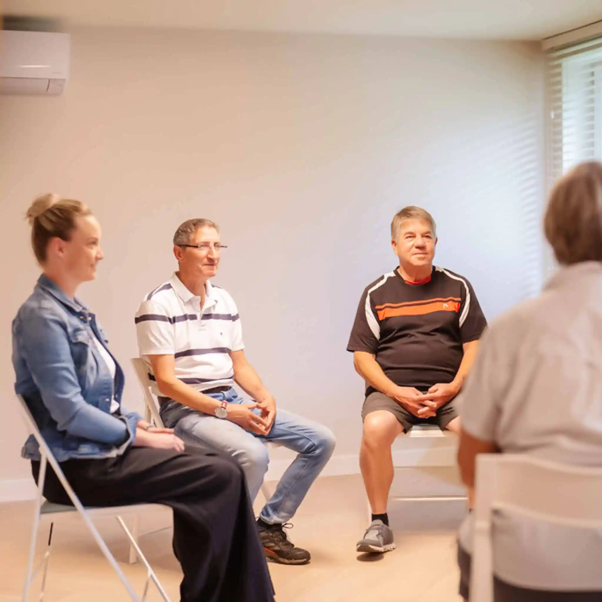 Mehrere Patienten sitzen bei einer Gruppentherapie im Sitzkreis.