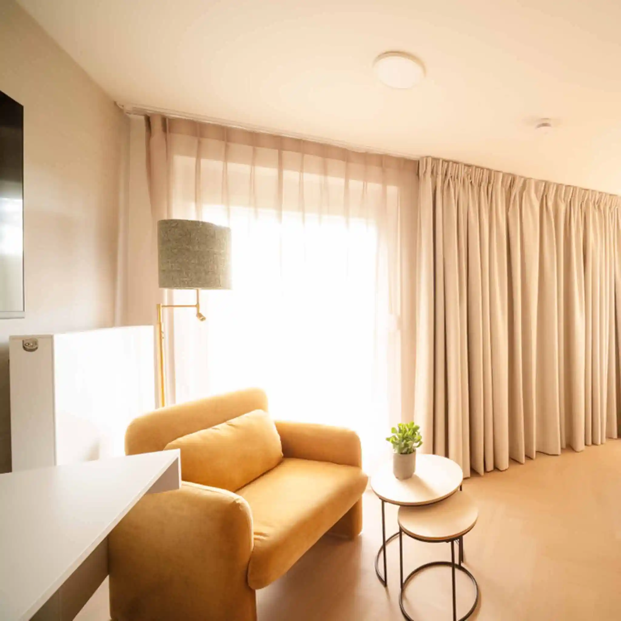 Gemütliche Sitzecke mit Sessel und Beistelltisch in einem Patientenzimmer.