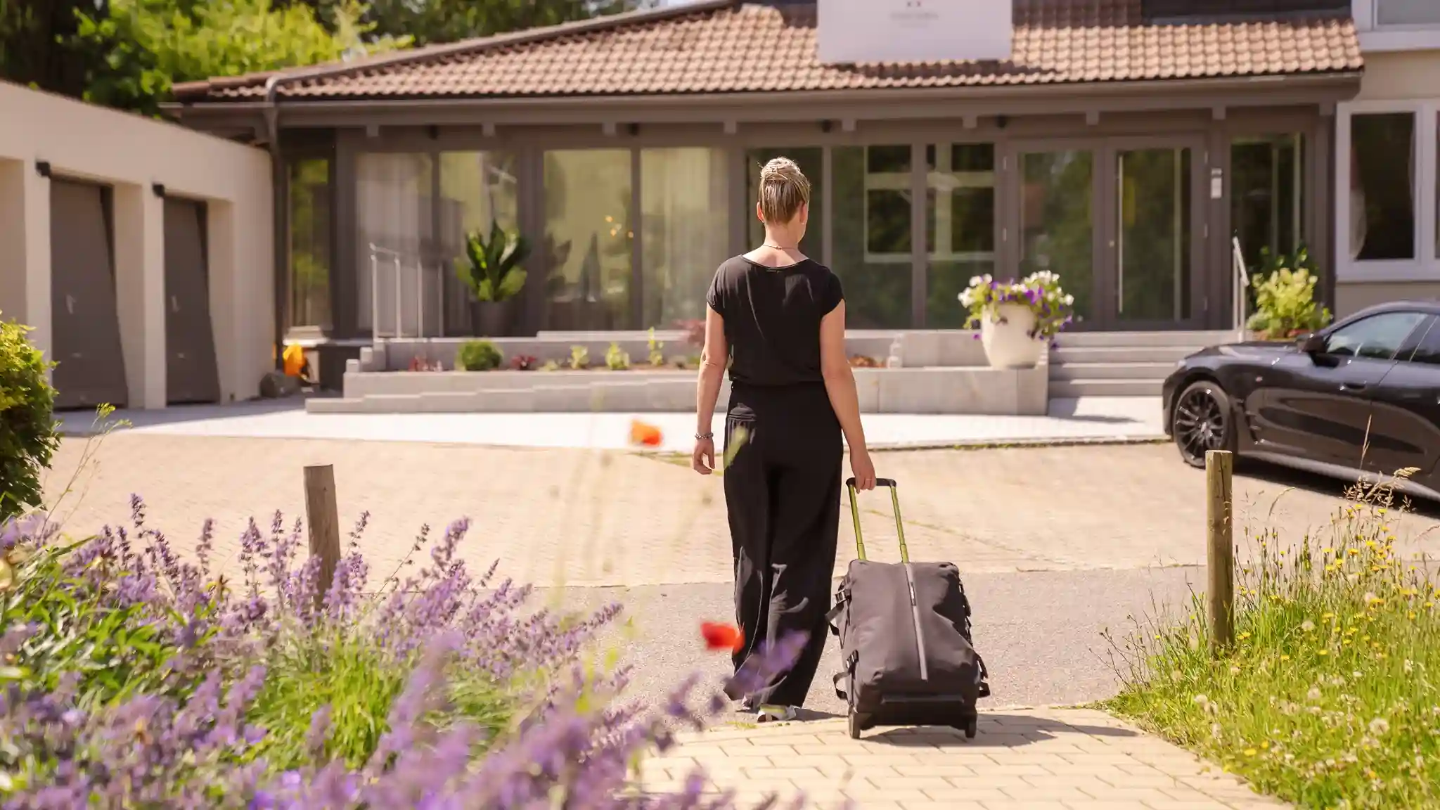 Eine Patientin bei der Anreise. Sie zieht ihren Koffer hinter sich her und läuft auf den Eingang zu.