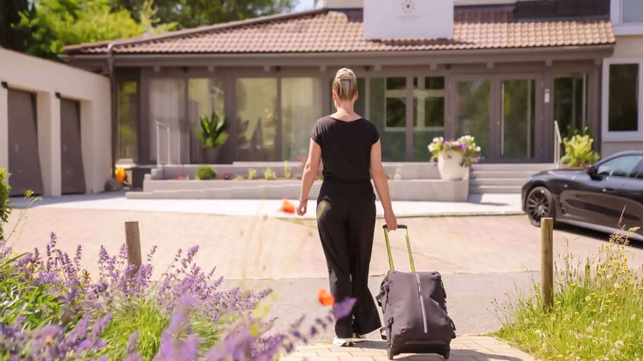 Eine Patientin bei der Anreise. Sie zieht ihren Koffer hinter sich her und läuft auf den Eingang zu.