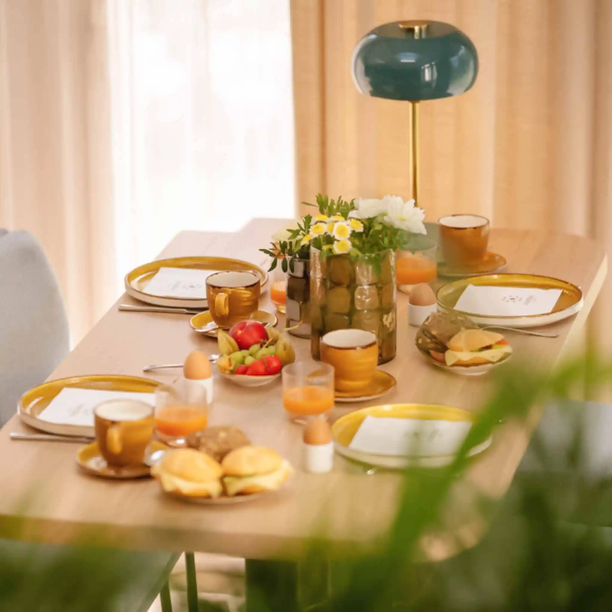 Ein gedeckter Frühstückstisch mit gekochten Eiern, Belegtenbrötchen und Saft