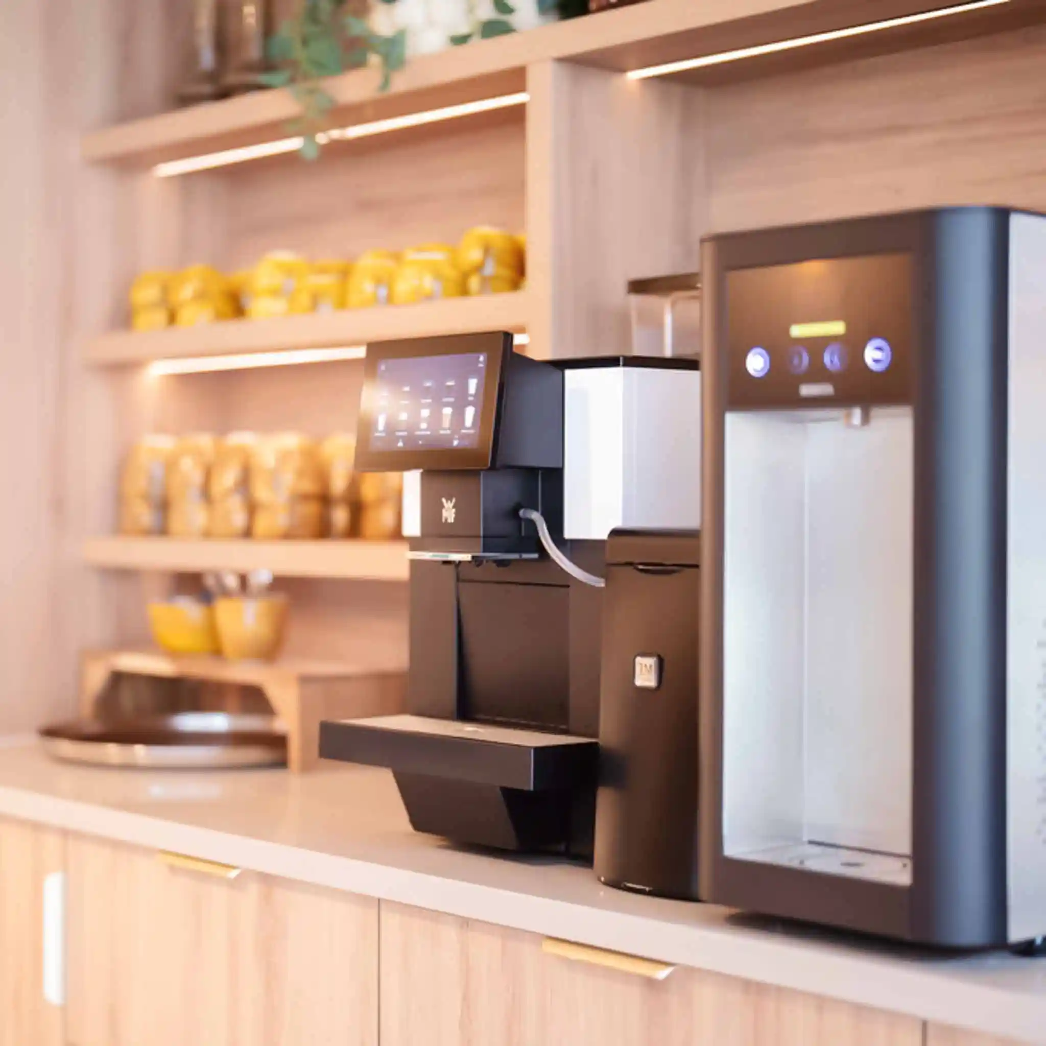 Ein Kaffeevollautomat, neben dem eine Reihe an gelben Tassen steht.