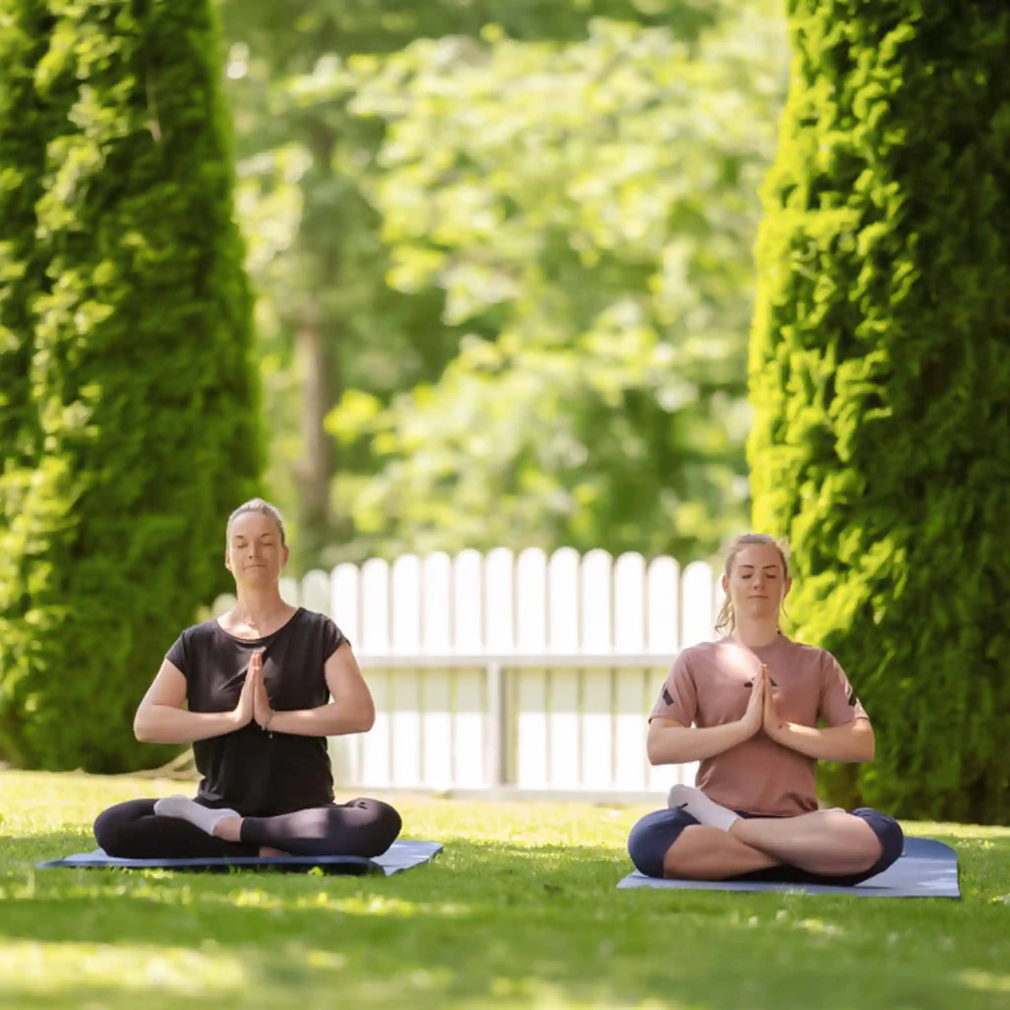 Zwei Frauen sitzen nebeneinander auf dem Boden und Meditieren.