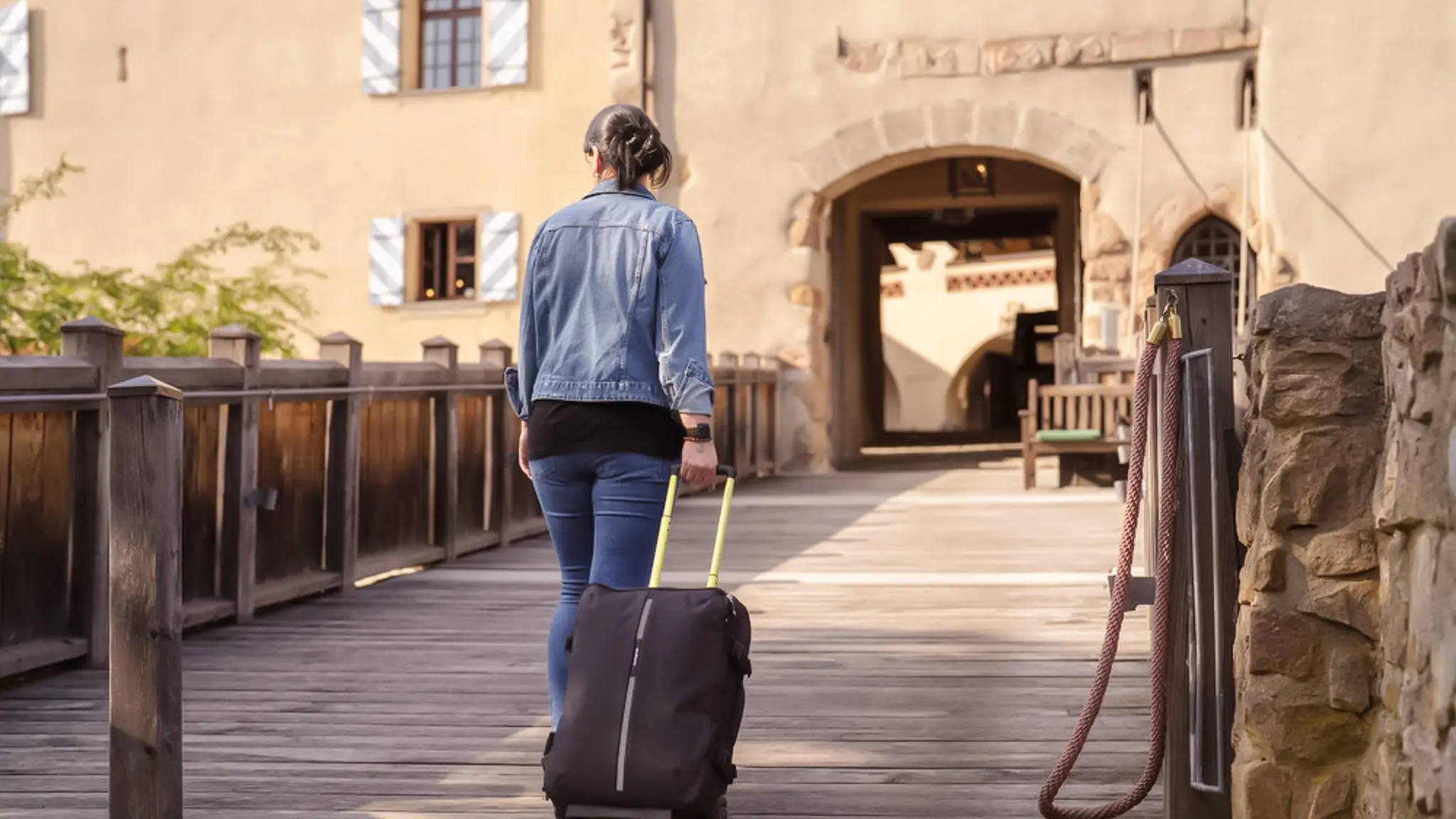 Eine Patientin läuft über die Burgbrücke auf den Eingang der Vincera Klinik Burg Wernberg zu.
