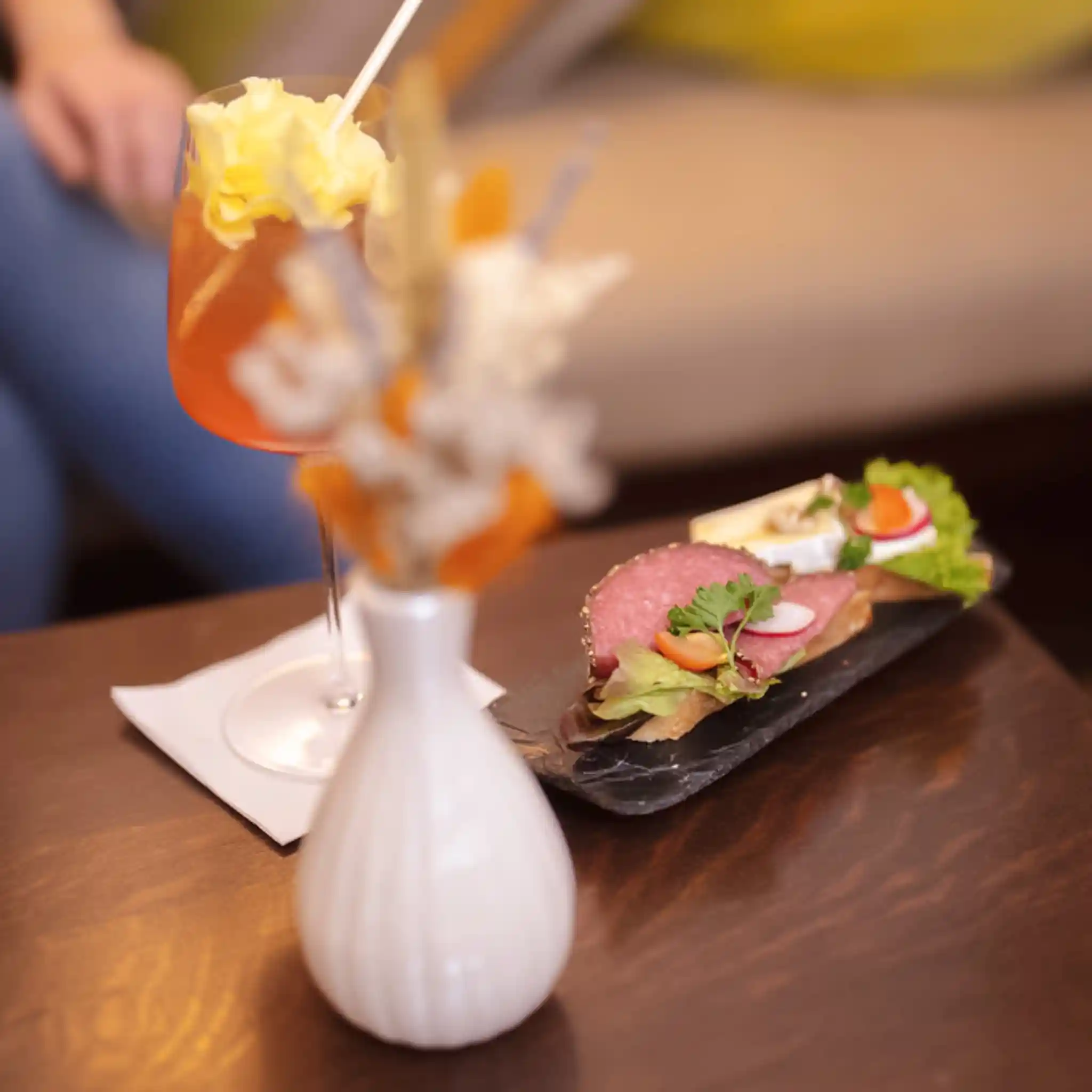 Ein Aperitif und ein belegtes Brot stehen auf einem Tisch.