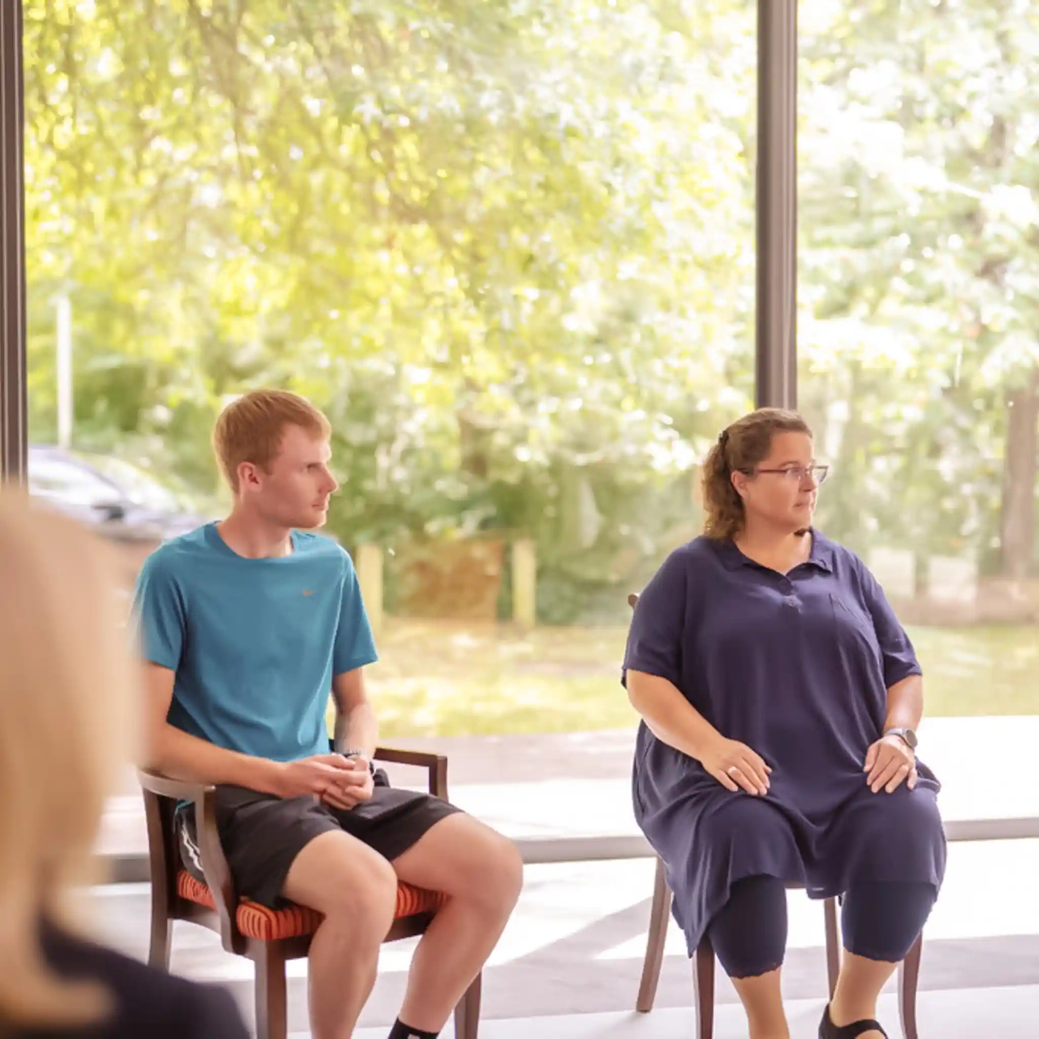 Mehrere Patienten sitzen bei einer Gruppentherapie im Stuhlkreis.