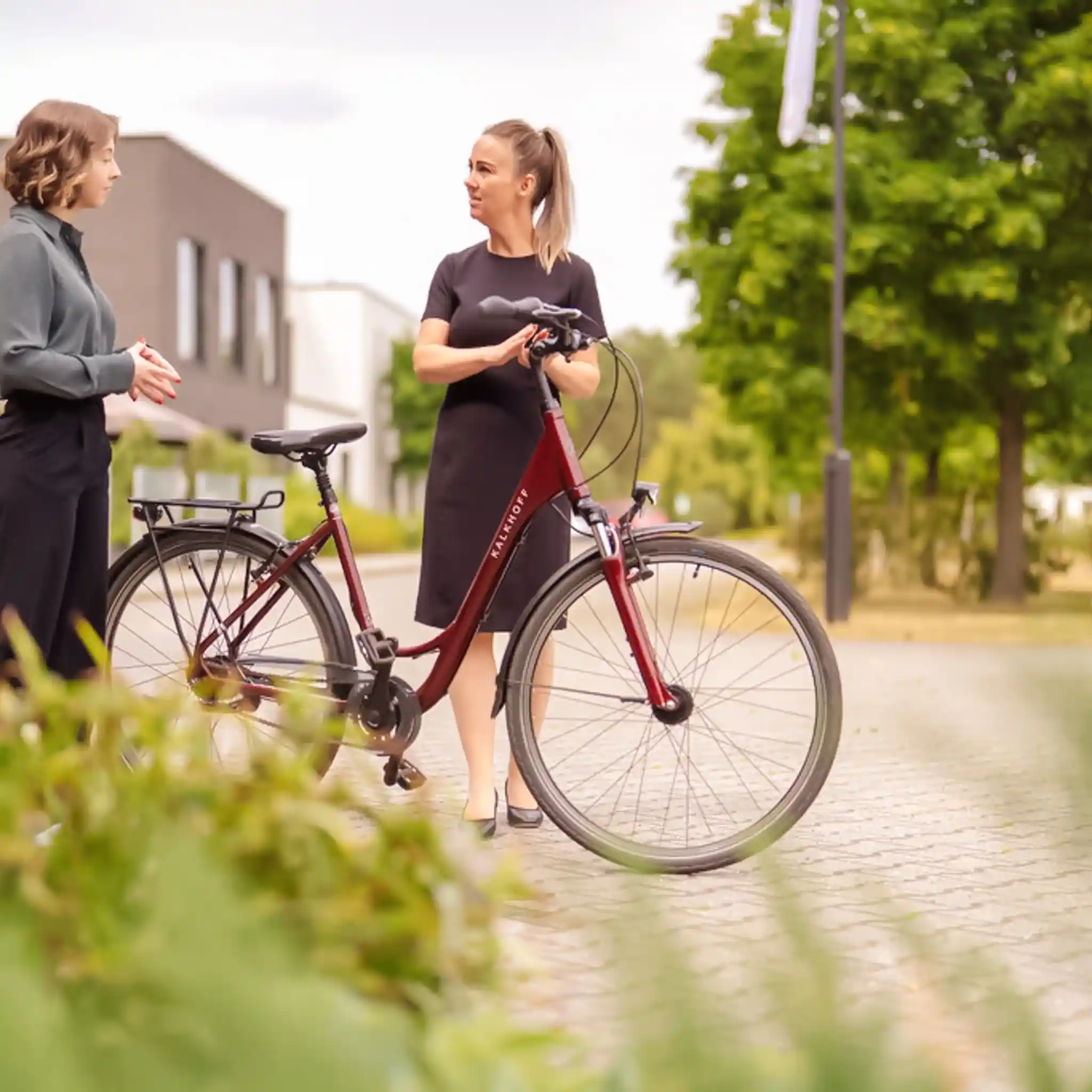 Zwei Frauen stehen neben einem Fahrrad und unterhalten sich.
