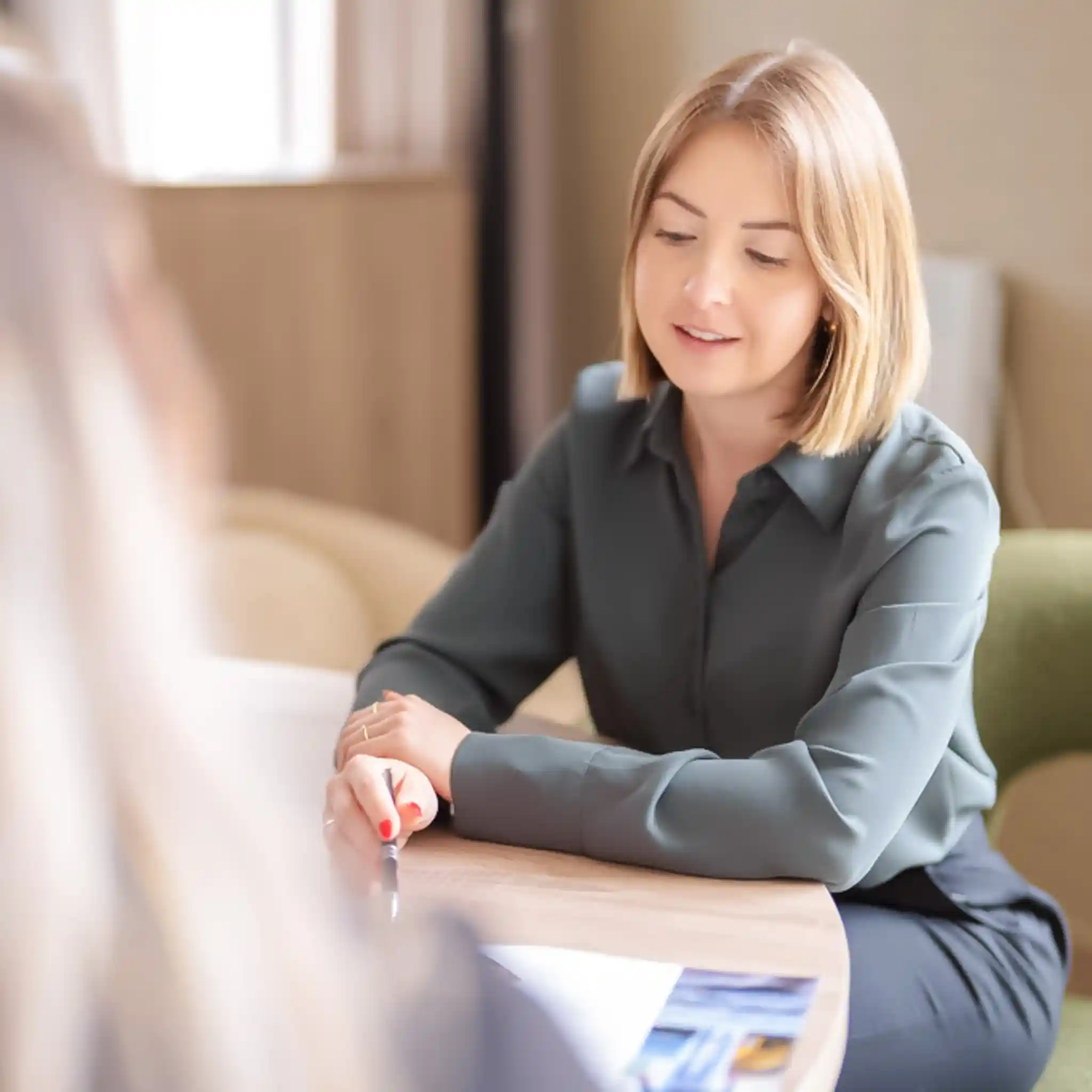 Eine Patientenmanagerin sitzt mit einer Patientin am Tisch und geht mit ihr die Klinikunterlagen durch.