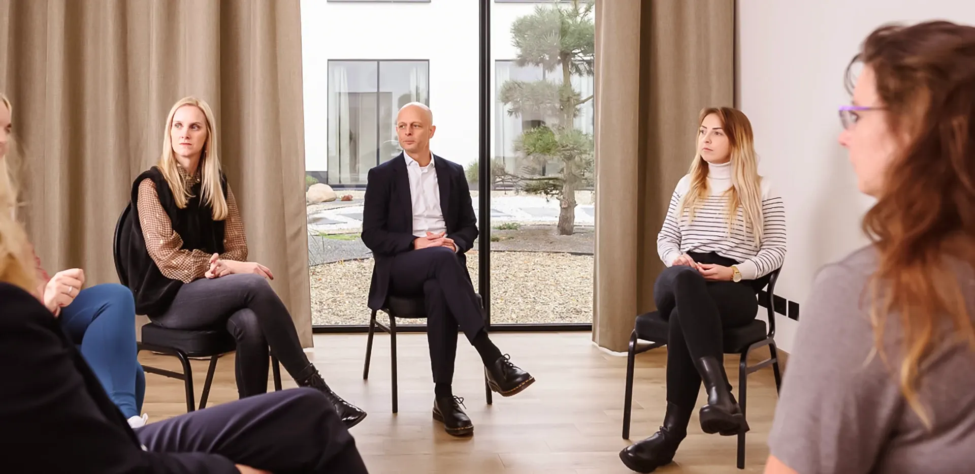 Gruppentherapie, bei der mehrere Patienten und ein Psychotherapeut in einem Sitzkreis sitzen.