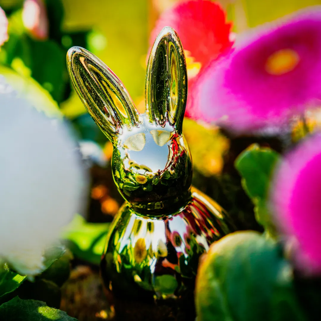 Eine Osterhasen-Figur sutzt zwischen Blumen