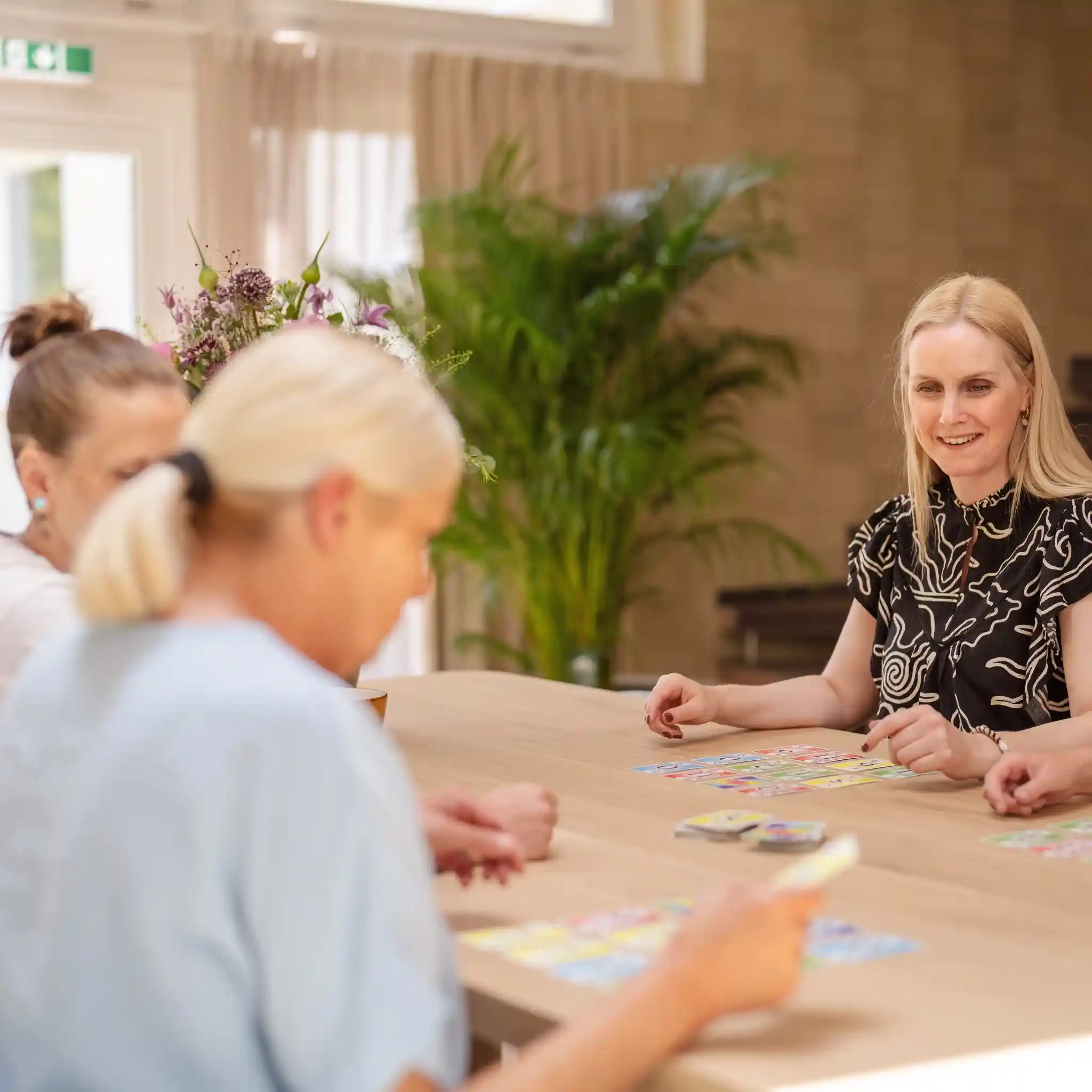 Mehrere Patienten sitzen an einem Tisch und spielen zusammen Karten.
