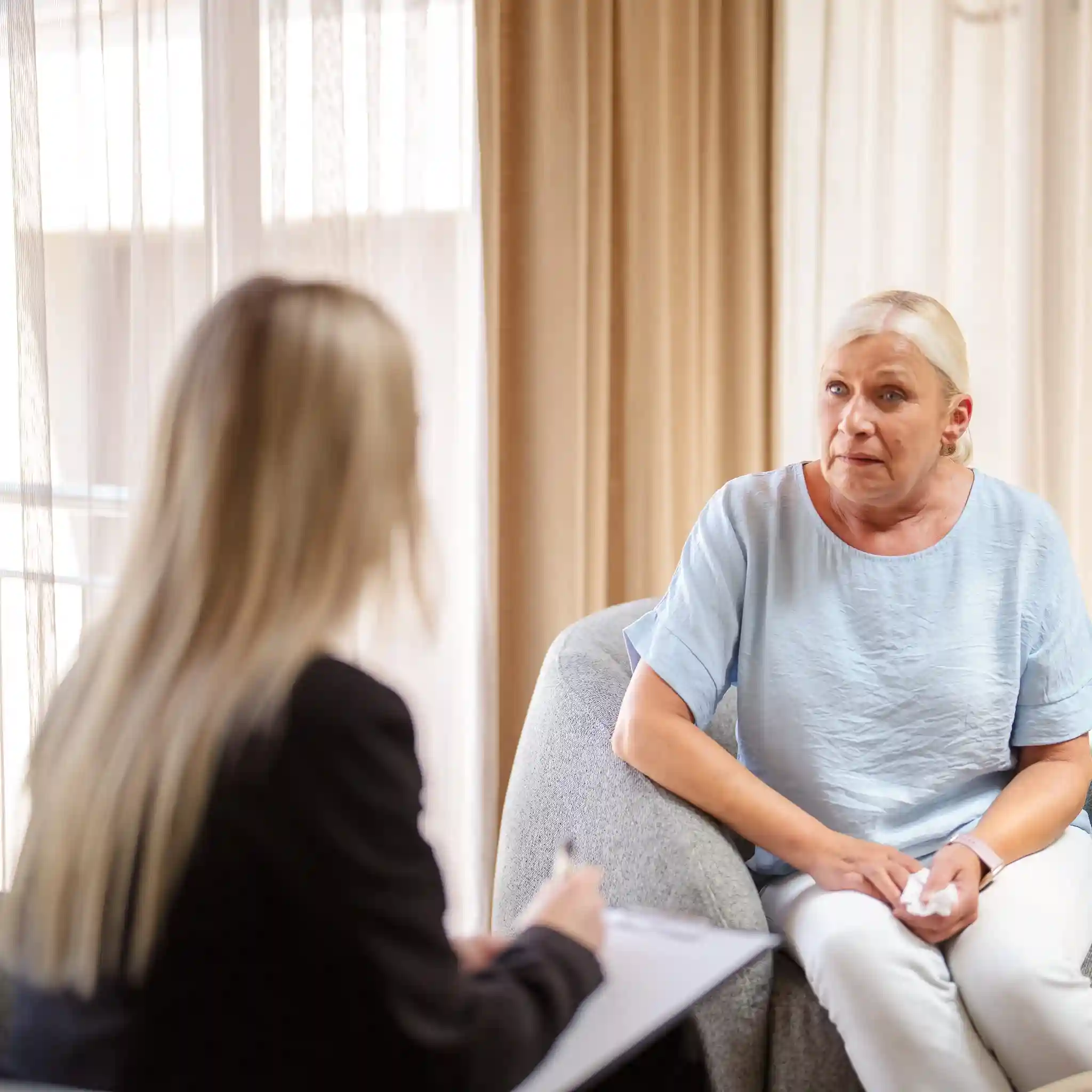 Eine Patientin sitzt in einer Einzeltherapiesitzung bei der Psychotherapie. In der Hand hält sie ein Taschentuch.