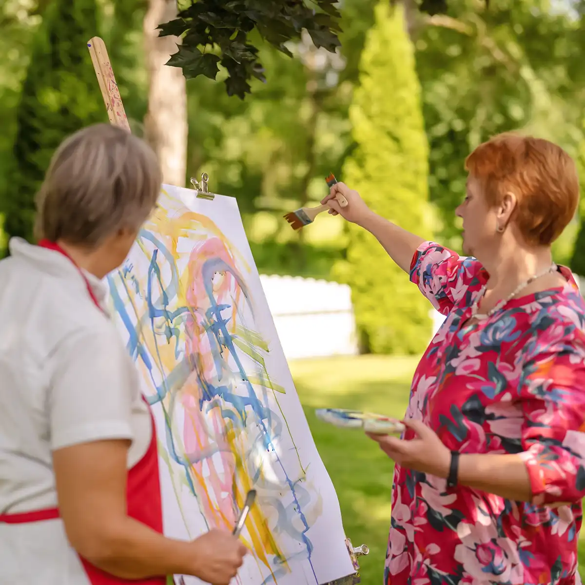Eine Patientin bemalt bei der Kunsttherapie eine Leinwand im Garten.