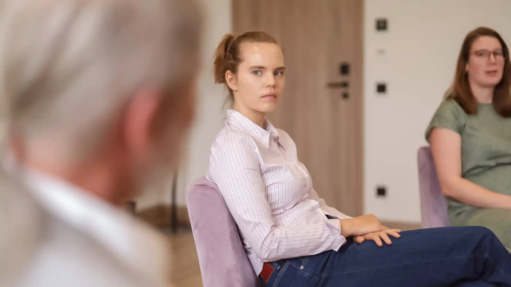 Eine junge Patientin sitzt bei der Gruppentherapie mit andern zusammen. 