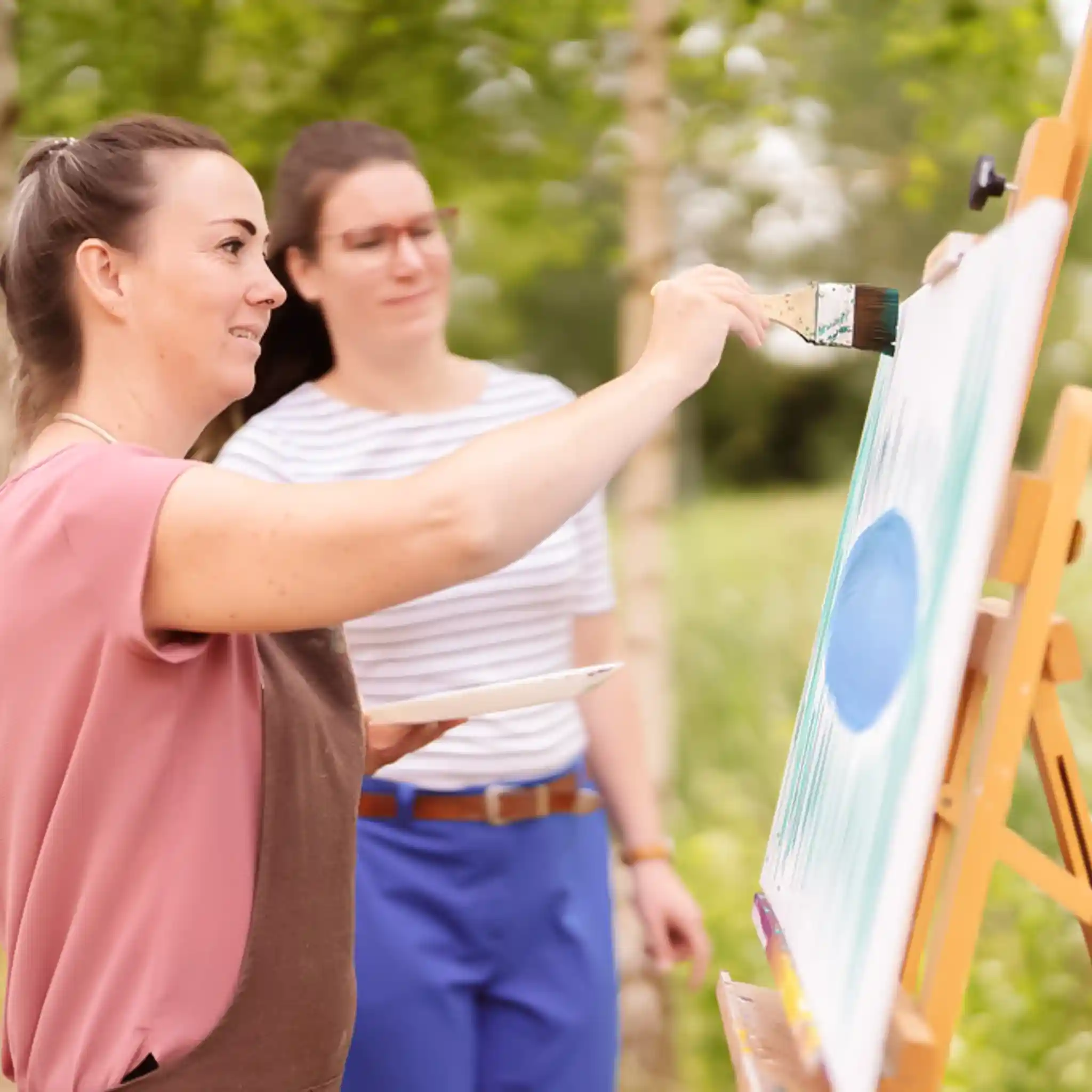 Eine Patientin malt im Rahmen der Kunsttherapie ein Bild auf einer Leinwand.