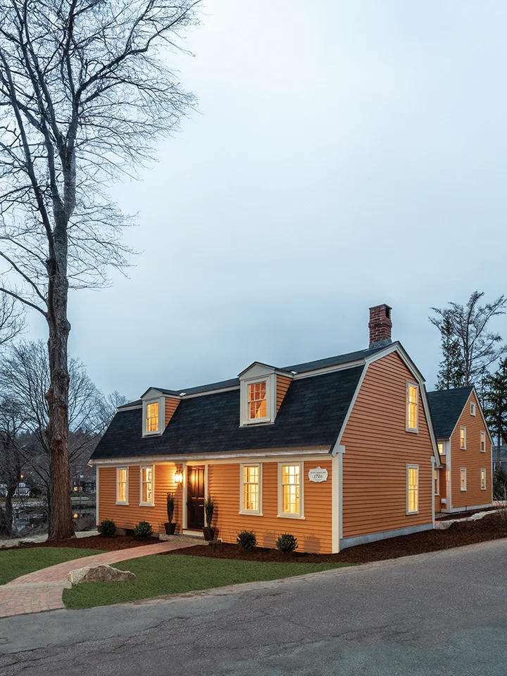 Finished historic-style home with warm lighting at dusk, ready for occupancy.