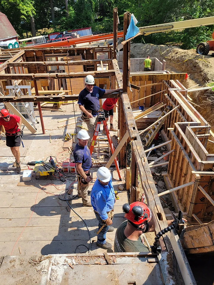 Construction crew working on a building site with wooden framing in progress.