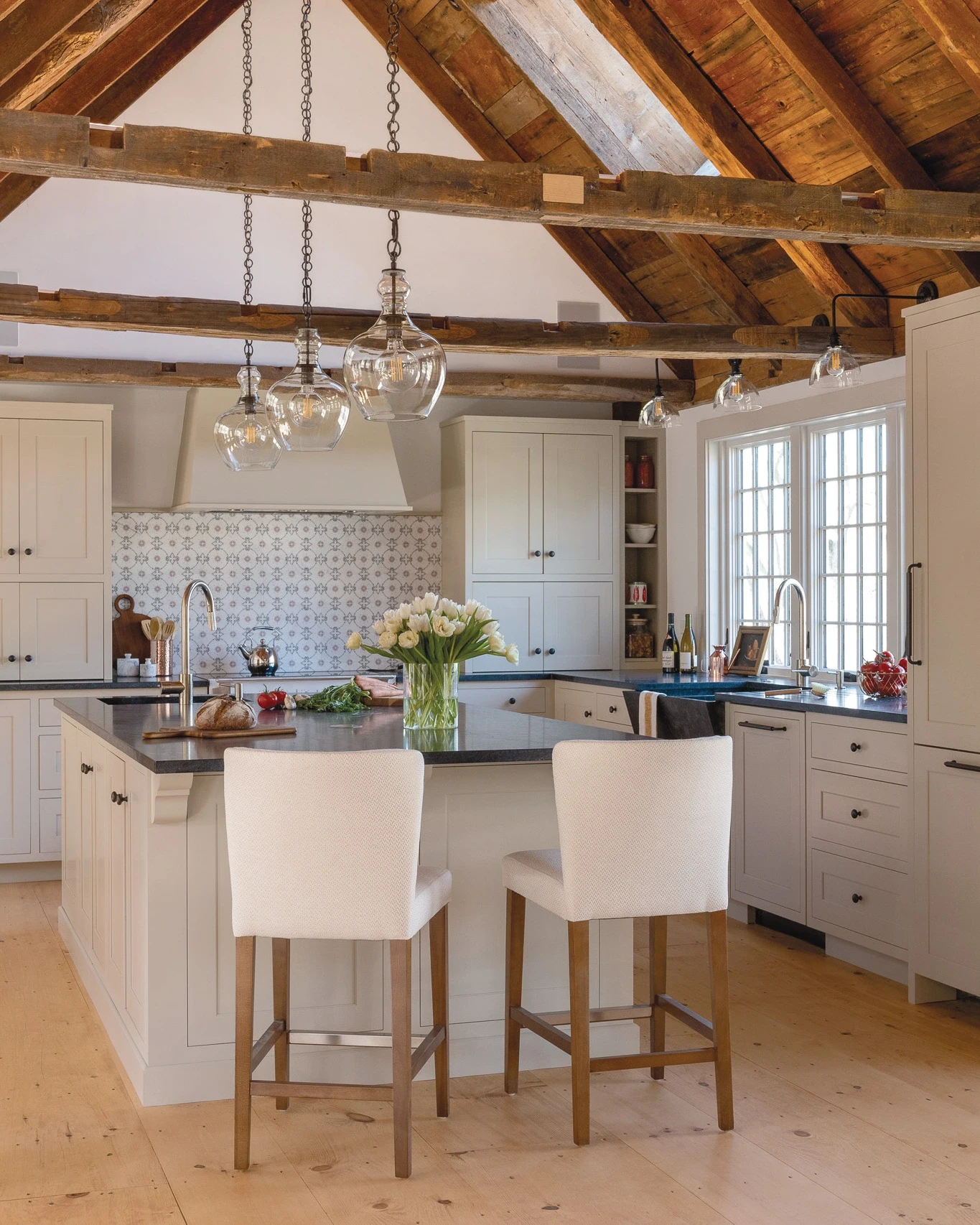 Restored 1720 Cape Ann Gambrel kitchen with exposed beams, pendant lighting, and center island
