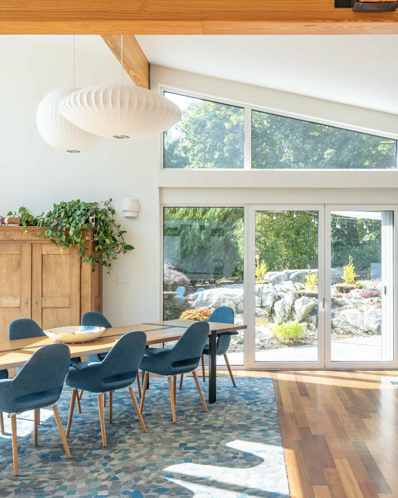 Bright dining space with mid-century design and full-height windows facing rock garden