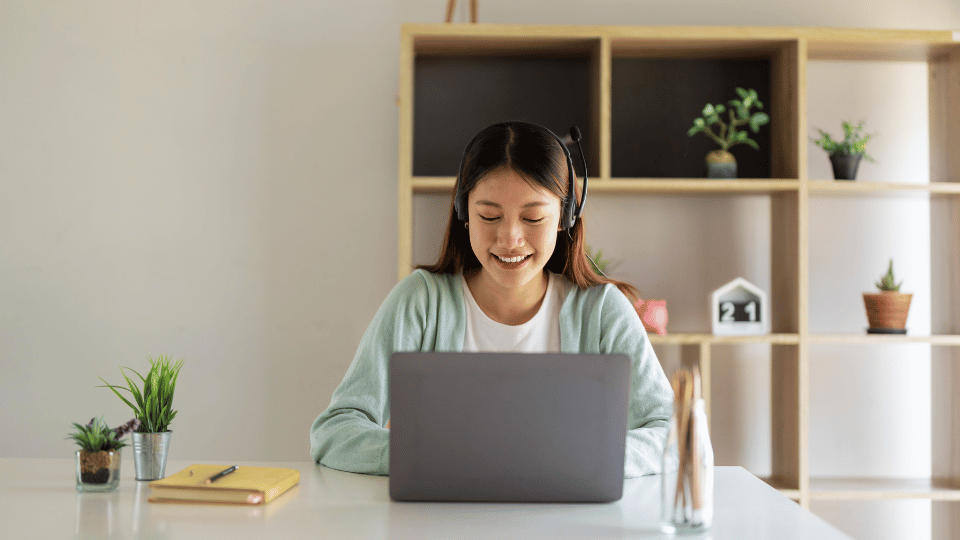 A woman seated at a desk, focused on her laptop, engaged in Saebo's Neurological and Hand Therapy Courses.