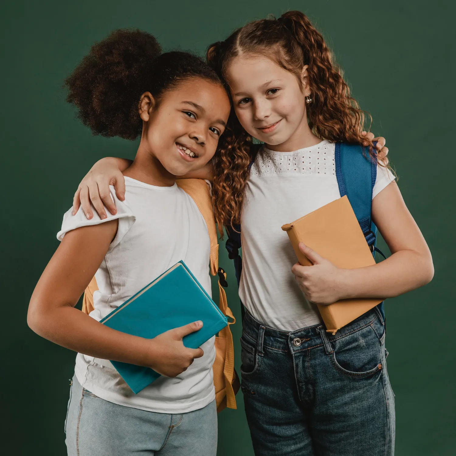 Two young girls standing next to each other holding books.