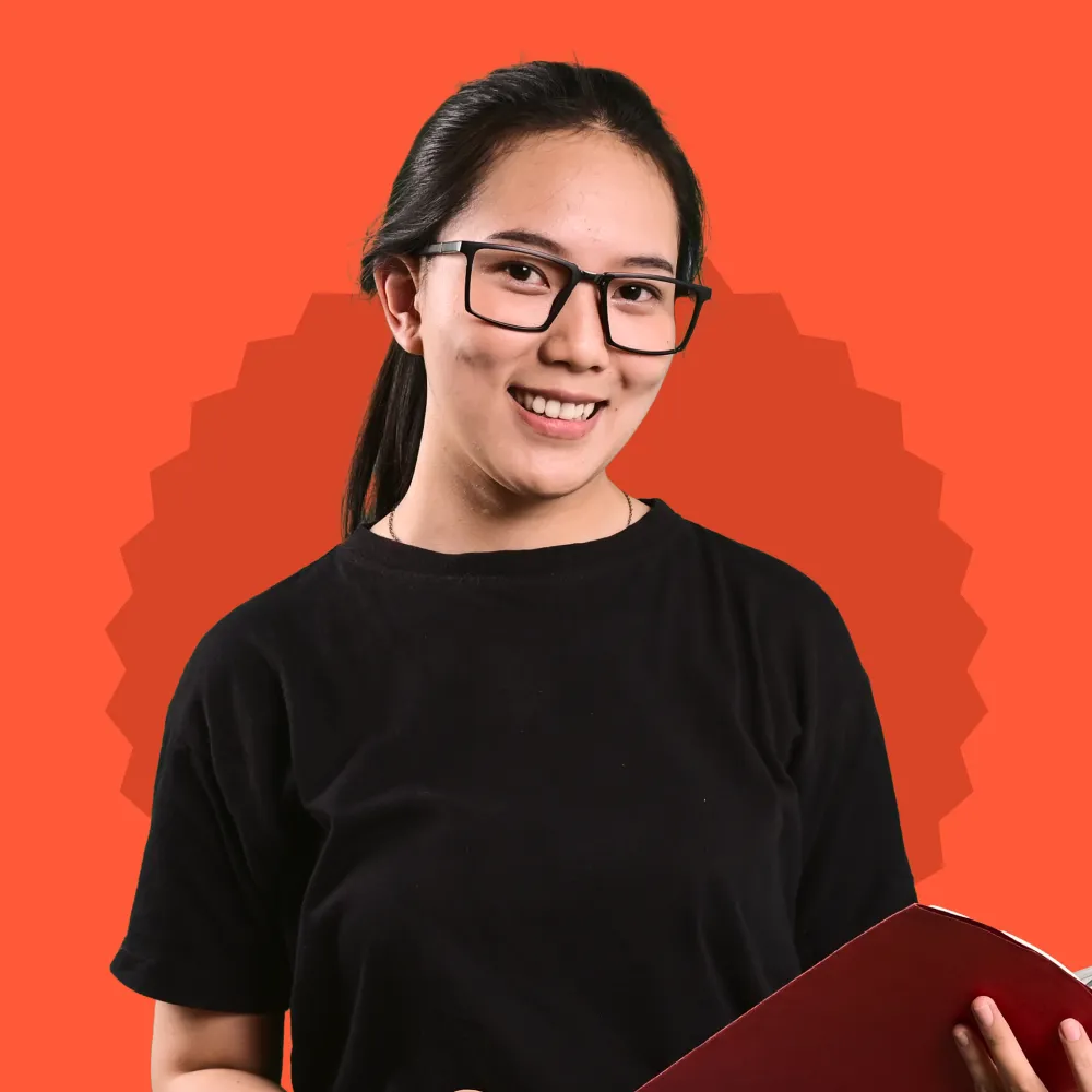 A woman wearing glasses holding a red folder.