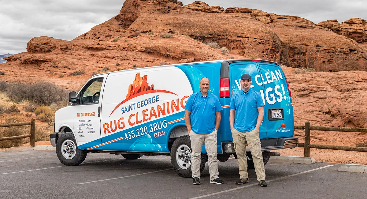 Two men standing with arms crossed in front of a Salt Lake City Rug Cleaning van parked outside.