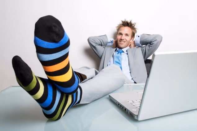 Man kicking his feet up on a desk with his arms behind his head, Encompass Web Services