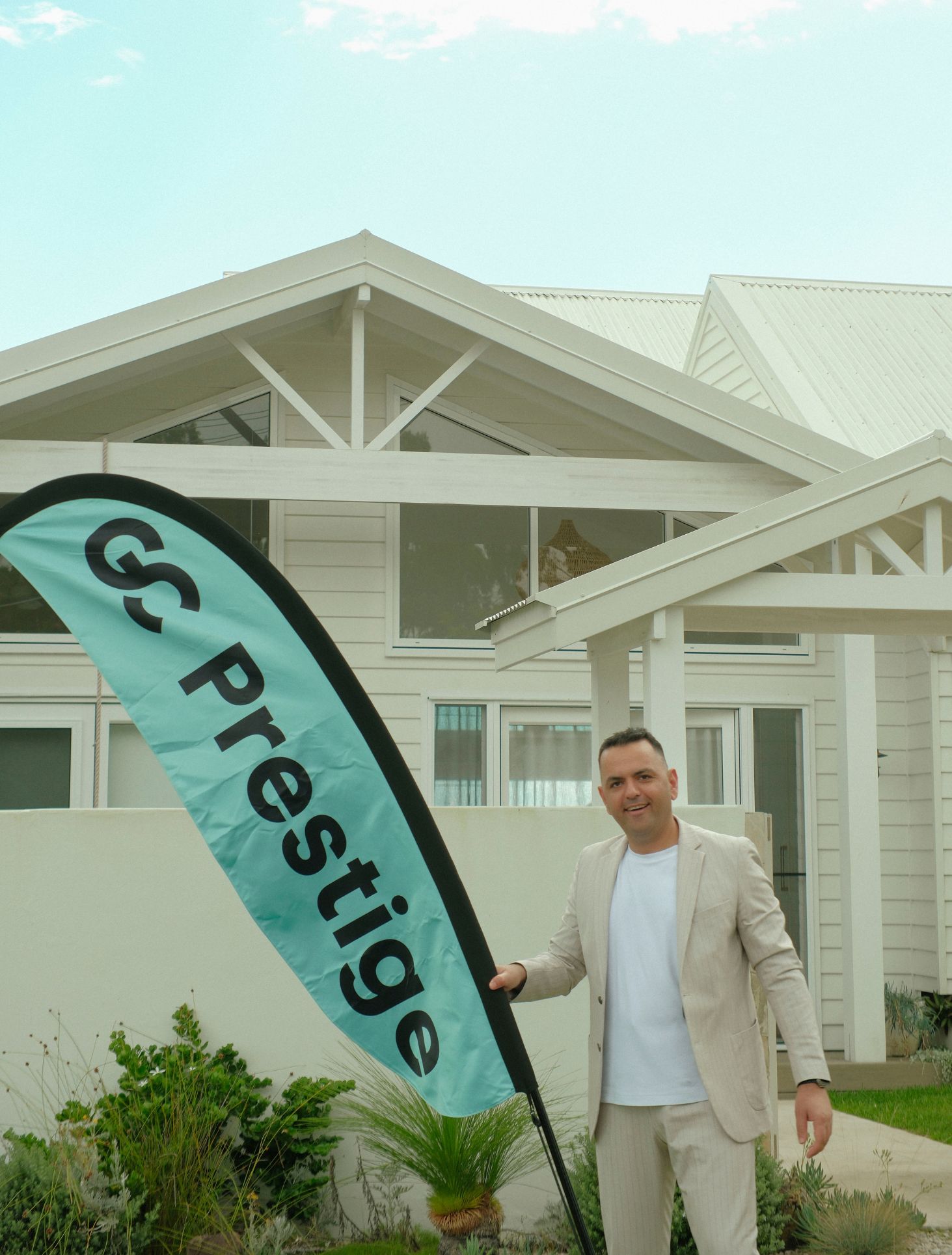 Oktay Vali of GC Prestige holding a GC Prestige flag outside a coastal home