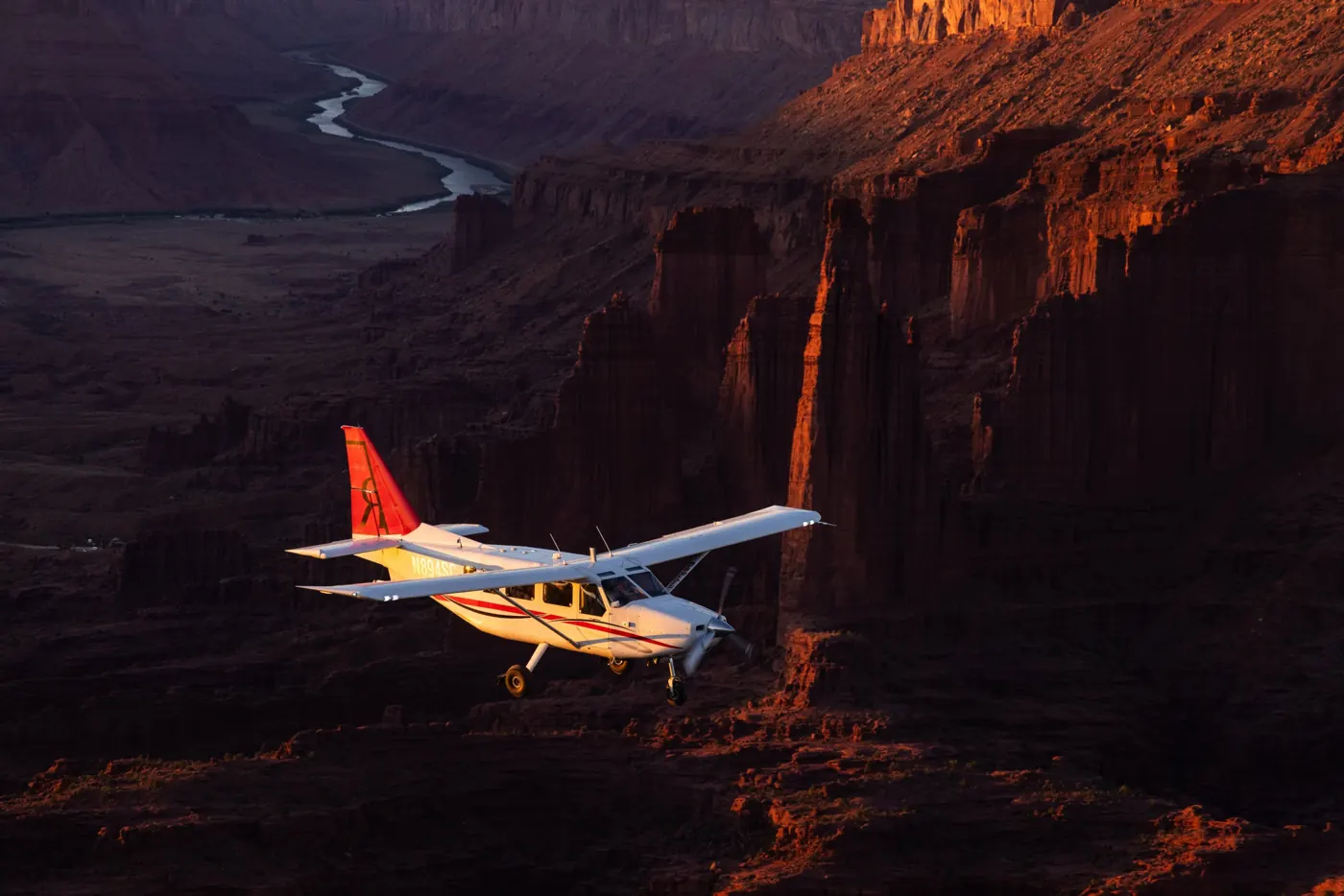 Redtail Air plane flying past red rock canyon walls near Moab at sunset